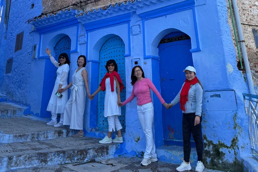 Camel Ride Trips travelers in front of blue doors in the Chefchaouen medina, day 3 of the 14-Day Morocco Tour from Casablanca: Morocco at Leisure