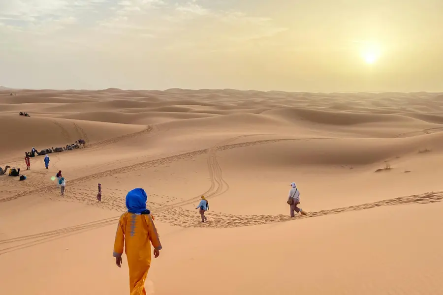 Travelers walking on the Erg Chebbi dunes toward the camels, Merzouga, day 7 of the 14-Day Morocco Tour from Casablanca: Morocco at Leisure