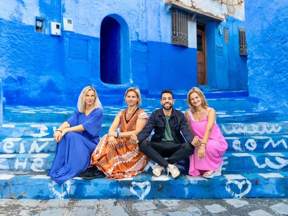 Travelers with their local guide on the blue steps of Chefchaouen during a 15-day private Morocco tour from Casablanca