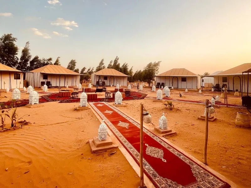 Desert camp with lanterns and Berber carpets at sunset in the Erg Chebbi dunes, Merzouga