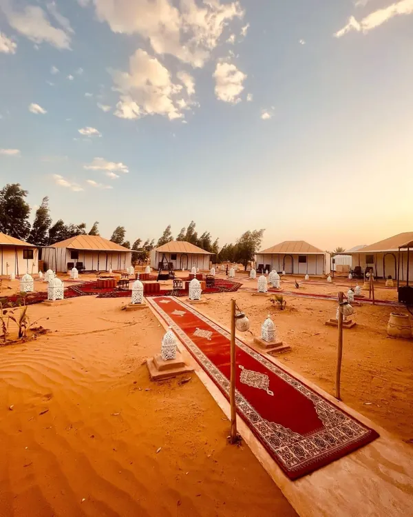 Desert camp with white tents, lanterns and carpets in the Erg Chebbi dunes, Merzouga