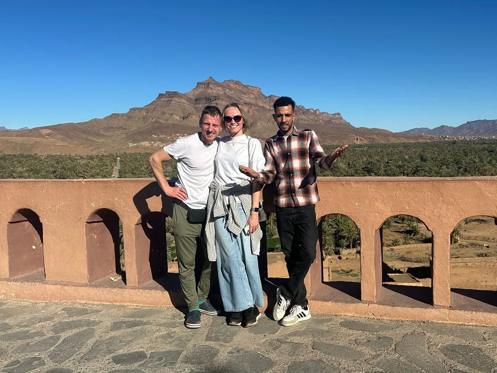 Travelers with their Camel Ride Trips driver-guide above the Draa Valley palm groves on an 8-day Morocco tour from Marrakech