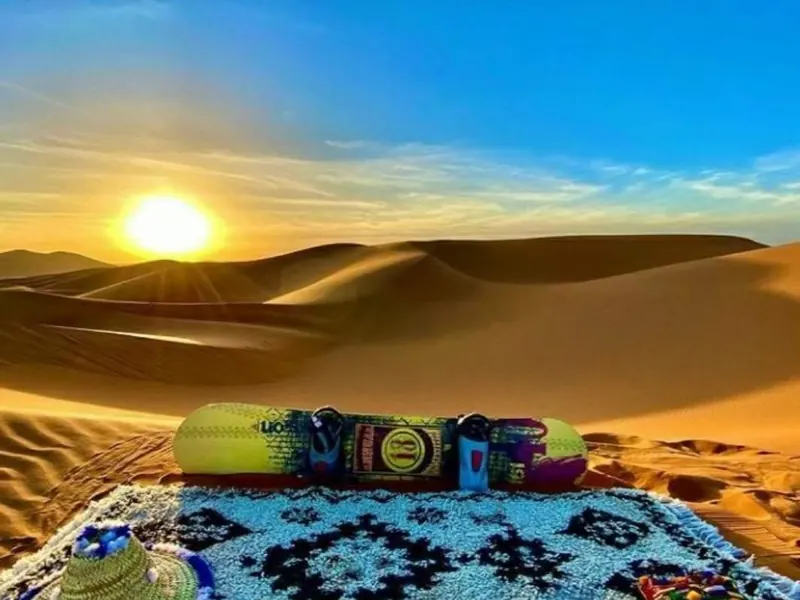 Sandboard and Berber carpet on the Erg Chebbi dunes at sunset in Merzouga