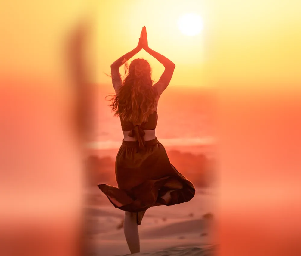 Woman in tree pose on a Sahara dune at sunset, yoga and wellness retreat in Morocco